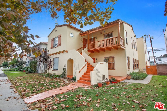 mediterranean / spanish-style house featuring a balcony and a front yard