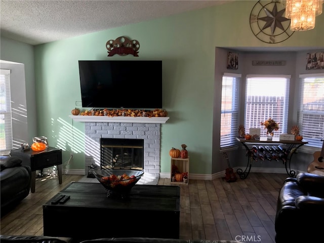 living room featuring a textured ceiling, vaulted ceiling, a brick fireplace, and hardwood / wood-style flooring