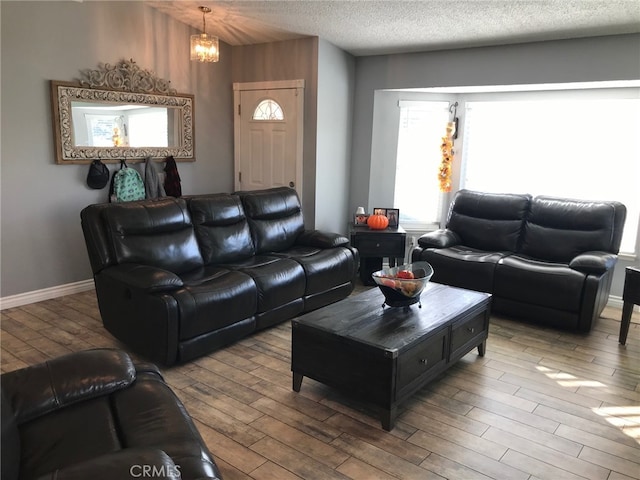 living room featuring a notable chandelier, a textured ceiling, and light hardwood / wood-style floors