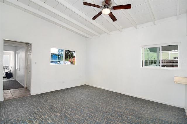 empty room with dark carpet, beam ceiling, wood ceiling, and ceiling fan