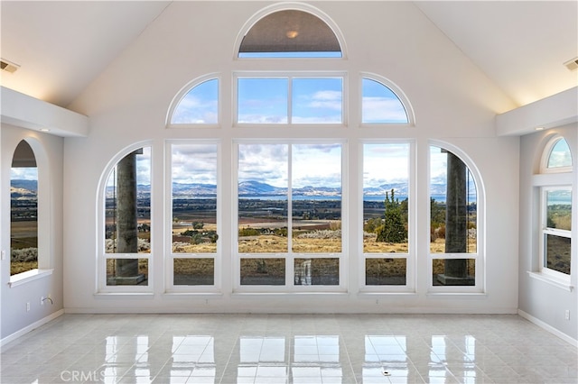 interior space with a wealth of natural light, a mountain view, and high vaulted ceiling