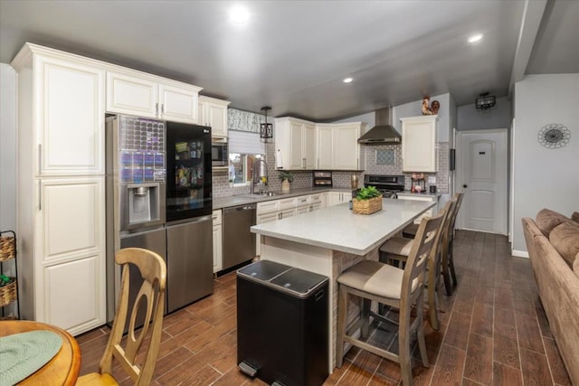 kitchen featuring wall chimney exhaust hood, a kitchen island, dark hardwood / wood-style flooring, white cabinetry, and stainless steel appliances