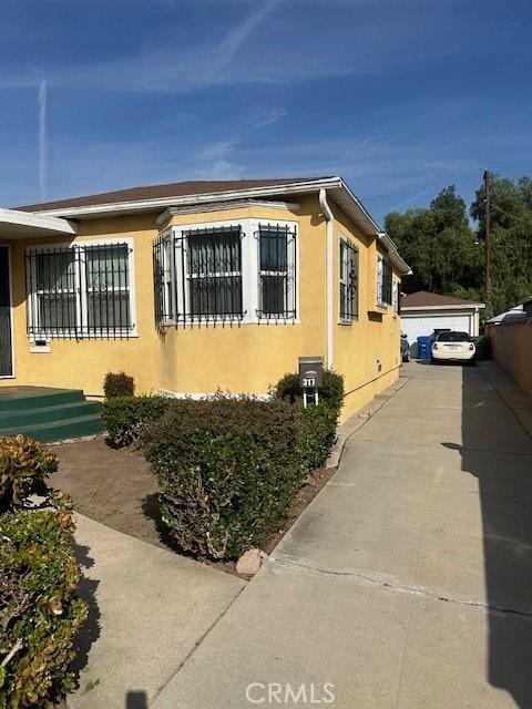 315 E 118th St, Los Angeles, CA 90061 - view of side of home featuring stucco siding and an outdoor structure