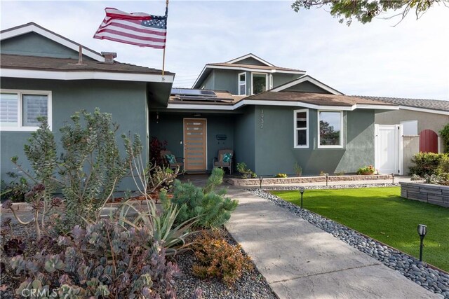 view of front of house featuring a front yard and solar panels