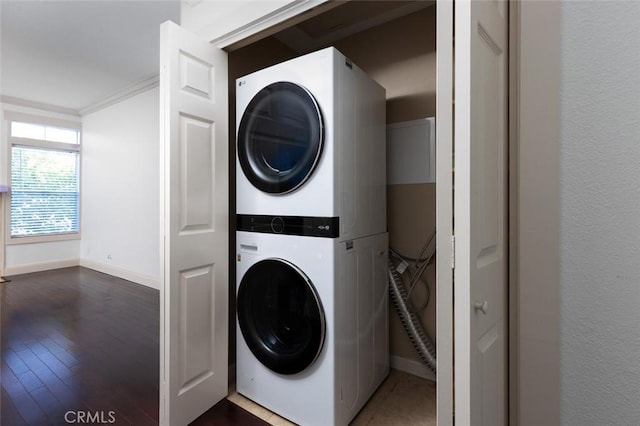 laundry room with ornamental molding, stacked washer and dryer, and dark wood-type flooring