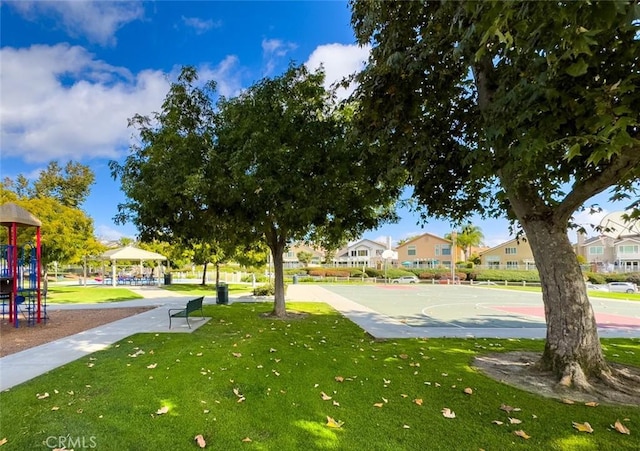 view of home's community featuring a lawn, basketball hoop, and a playground