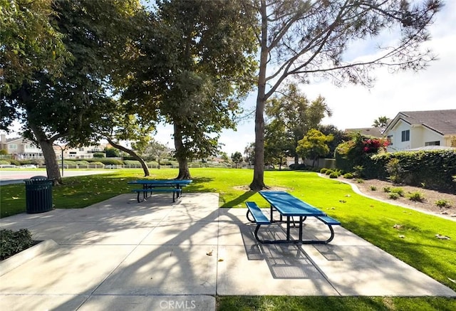 view of property's community featuring a lawn and a patio