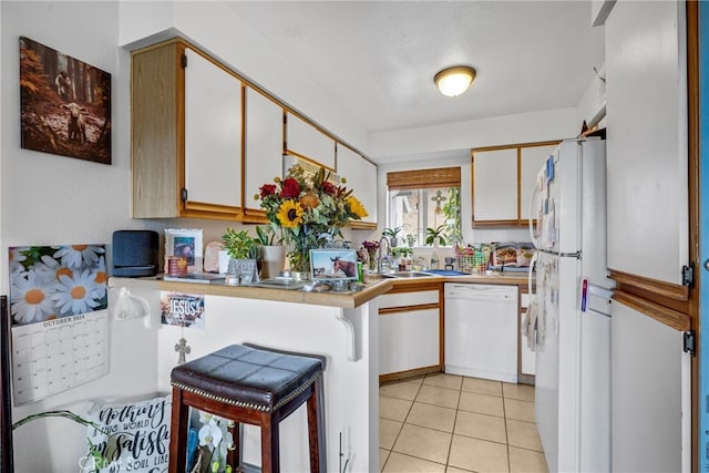 kitchen with white appliances, white cabinetry, kitchen peninsula, and a kitchen bar