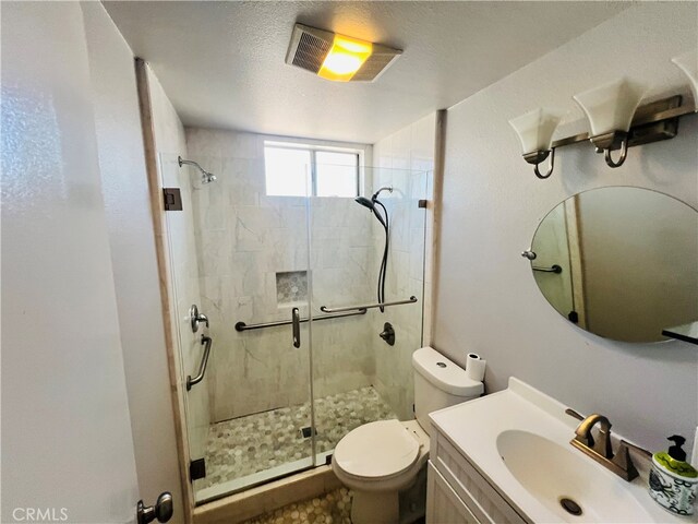 bathroom featuring a shower with door, vanity, a textured ceiling, and toilet