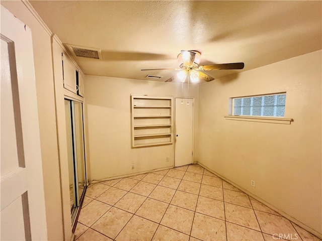 tiled empty room featuring ceiling fan and a textured ceiling