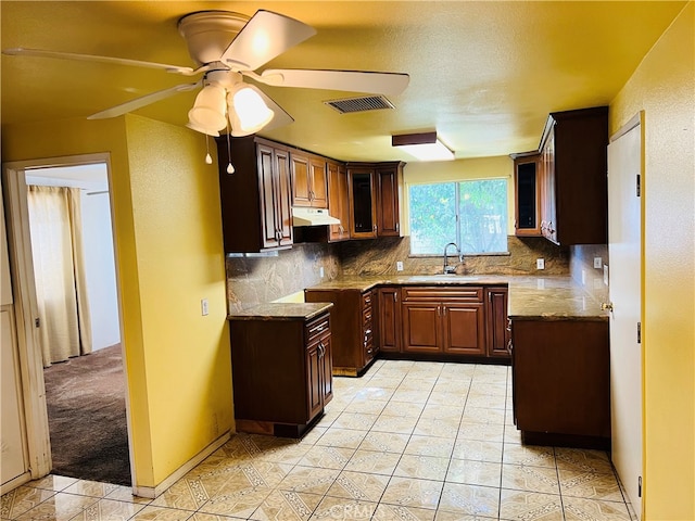 kitchen featuring tasteful backsplash, sink, ceiling fan, light carpet, and light stone counters