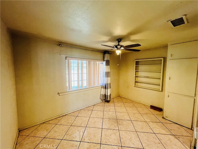 tiled empty room featuring a textured ceiling and ceiling fan