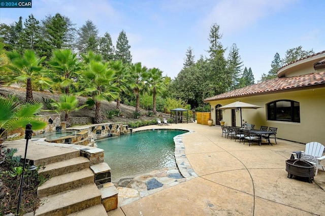 view of swimming pool featuring a fire pit, an in ground hot tub, and a patio