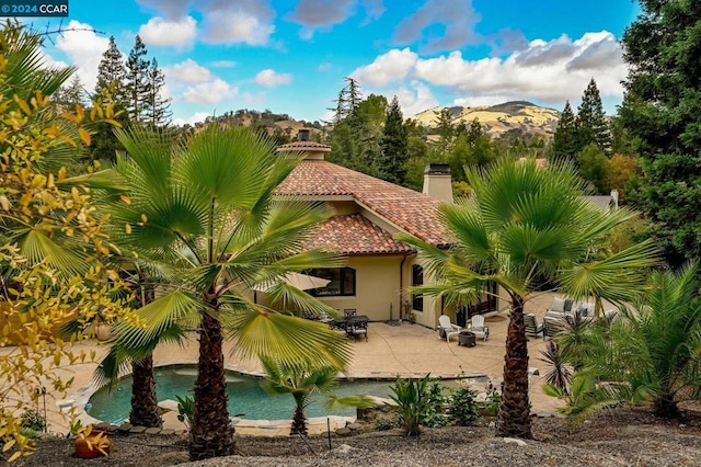 rear view of house featuring a mountain view and a patio area