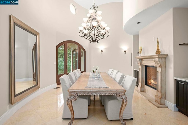 dining room featuring a notable chandelier, a fireplace, and a high ceiling