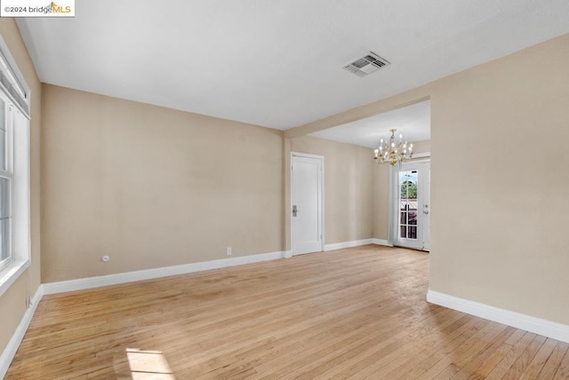 empty room featuring a chandelier and light hardwood / wood-style flooring