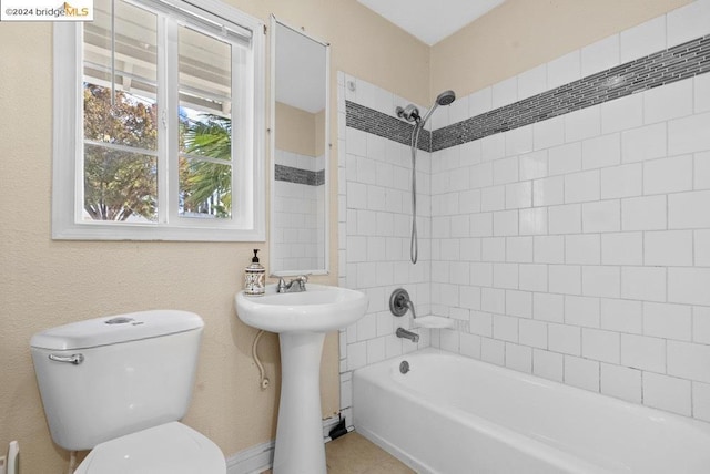 full bathroom featuring tiled shower / bath combo, toilet, and sink