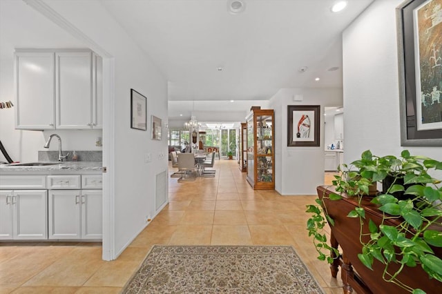 hall with sink, a notable chandelier, and light tile patterned flooring