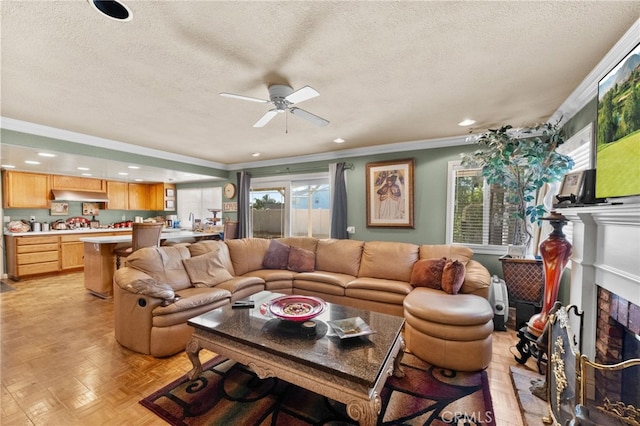 living room with crown molding, a textured ceiling, a brick fireplace, and ceiling fan