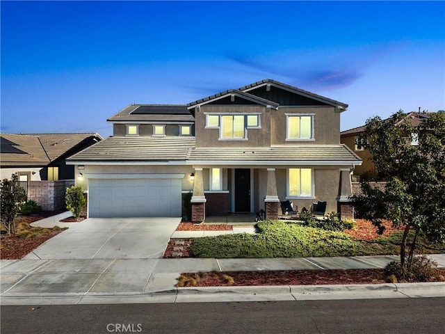 craftsman-style house featuring covered porch, solar panels, and a garage