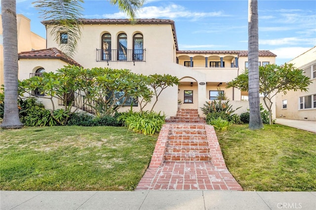 mediterranean / spanish house featuring a balcony and a front lawn