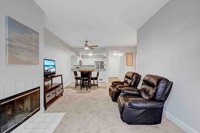 living room featuring light carpet, a tile fireplace, and ceiling fan