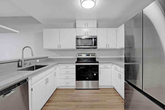 kitchen with white cabinetry, stainless steel appliances, sink, and light wood-type flooring