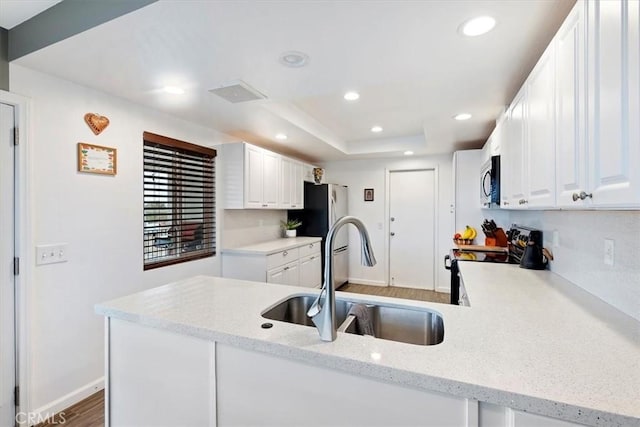 kitchen featuring white cabinetry, sink, kitchen peninsula, black electric range, and light stone counters