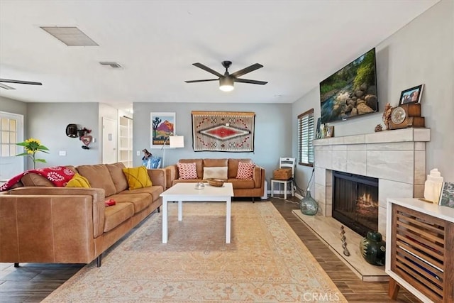 living room featuring ceiling fan, dark hardwood / wood-style floors, and a tile fireplace