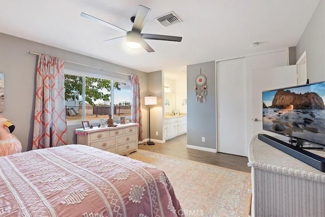 bedroom featuring ceiling fan, light hardwood / wood-style floors, and ensuite bath