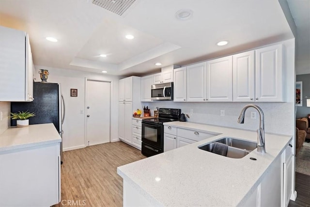 kitchen featuring white cabinetry, light hardwood / wood-style floors, a raised ceiling, black electric range oven, and sink