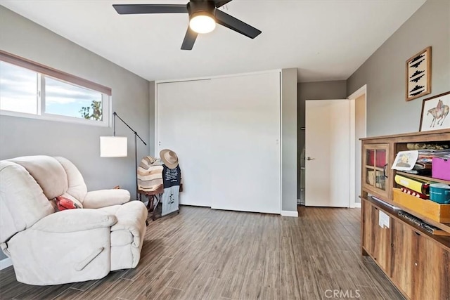 living area featuring ceiling fan and dark wood-type flooring