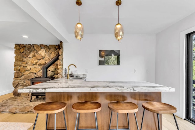 kitchen with a breakfast bar area, light hardwood / wood-style flooring, hanging light fixtures, kitchen peninsula, and sink