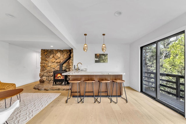 bar featuring light hardwood / wood-style flooring, sink, and hanging light fixtures