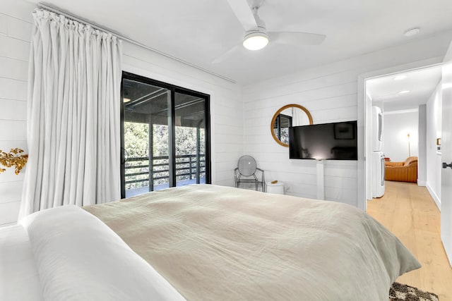 bedroom featuring access to outside, wood walls, light wood-type flooring, and ceiling fan