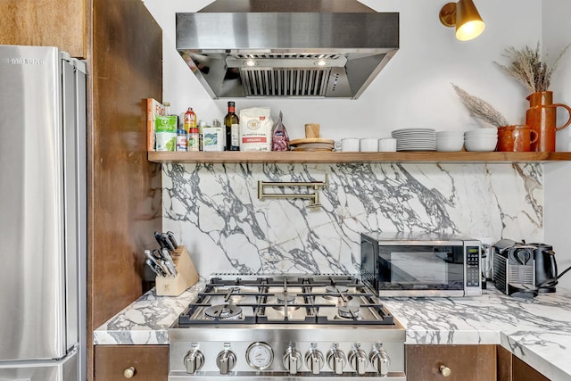 kitchen with decorative backsplash, light stone countertops, stainless steel appliances, and range hood