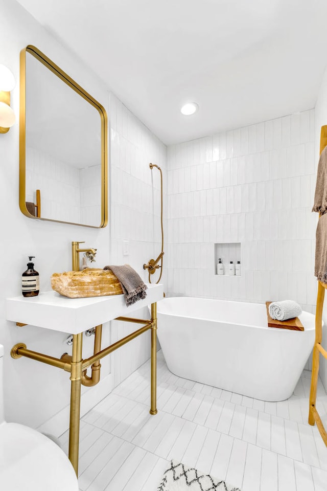 bathroom with a bath, toilet, tile patterned floors, and tile walls