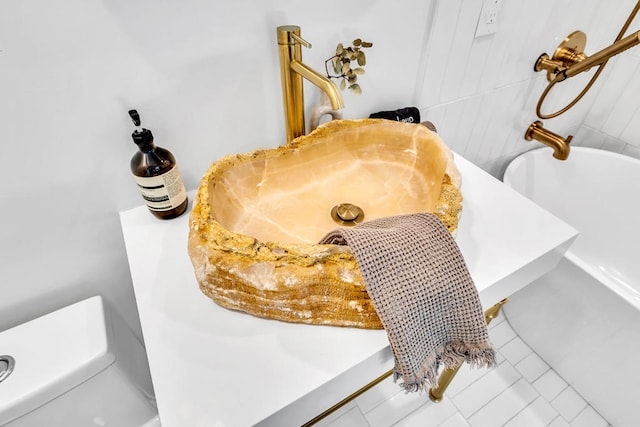 interior details featuring a bathtub, toilet, and tile patterned flooring