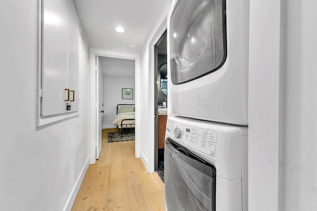 washroom featuring light hardwood / wood-style floors and stacked washer and clothes dryer