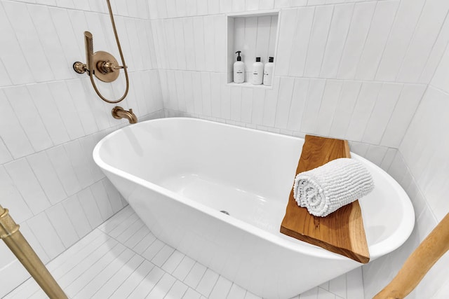 bathroom featuring tile walls, tile patterned flooring, and a bathing tub