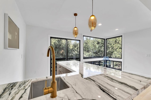 kitchen with light stone countertops, sink, and pendant lighting