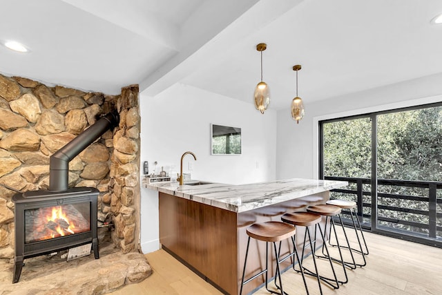 kitchen featuring light stone counters, light wood-type flooring, sink, and kitchen peninsula