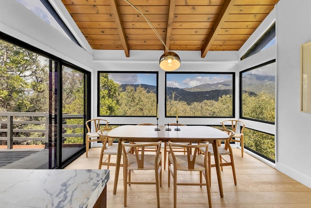 sunroom / solarium with wood ceiling, lofted ceiling with beams, a mountain view, and a wealth of natural light