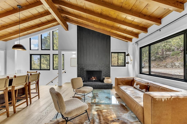 living room featuring light hardwood / wood-style flooring, vaulted ceiling with beams, a fireplace, and wooden ceiling