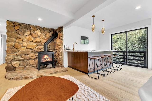 bar with sink, hanging light fixtures, and light hardwood / wood-style floors