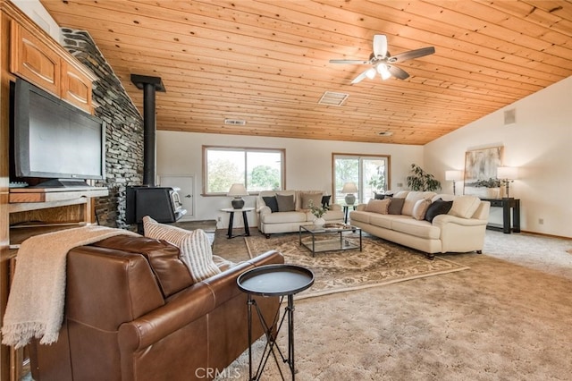 carpeted living room with a wood stove, ceiling fan, wood ceiling, and vaulted ceiling