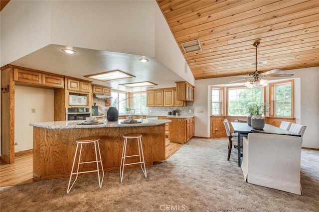 kitchen featuring light carpet, oven, a center island, and white microwave