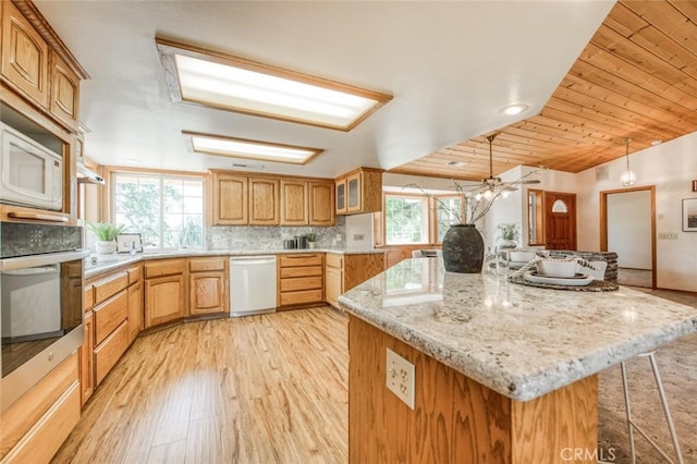 kitchen with wood ceiling, a healthy amount of sunlight, hanging light fixtures, and white appliances