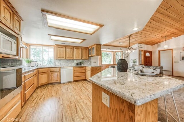 18486 Tollhouse Rd, Clovis, CA 93619 - kitchen featuring white dishwasher, stainless steel oven, light wood finished floors, a kitchen bar, and backsplash