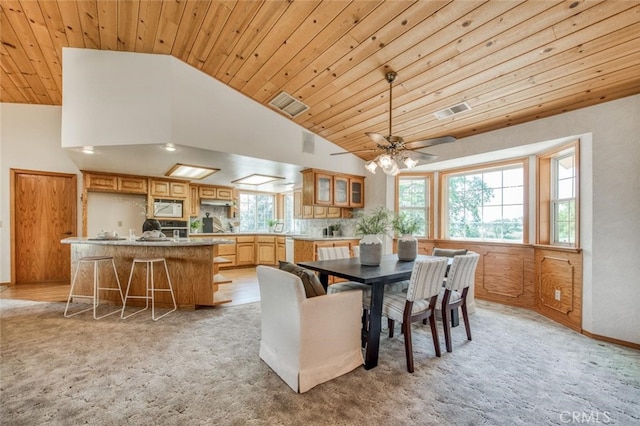 carpeted dining area with wood ceiling, high vaulted ceiling, and ceiling fan